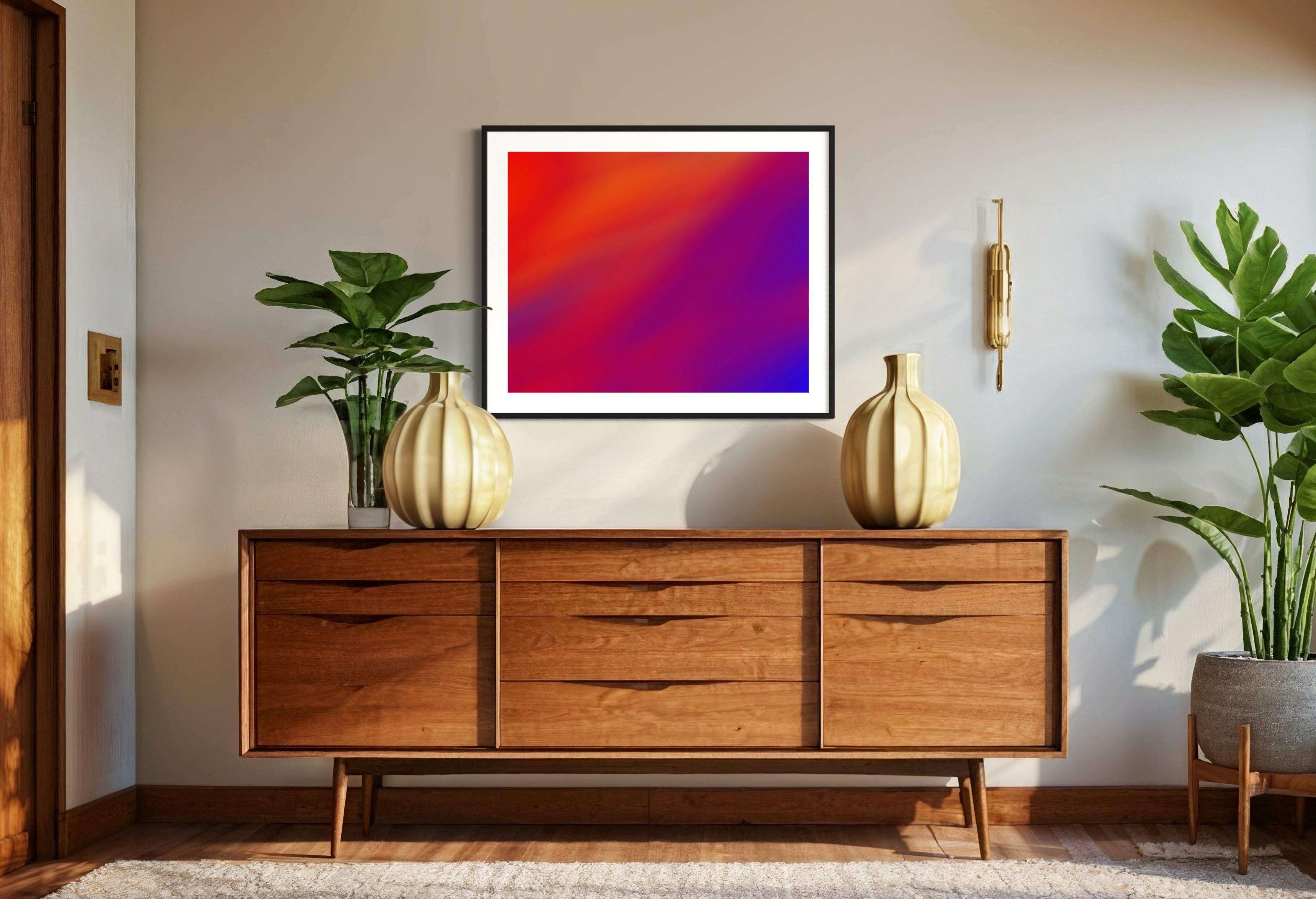 photo of abstract orange, yellow and purple in black frame with white matte on white wall above wooden furniture with drawers, plant on top, large plant on floor 