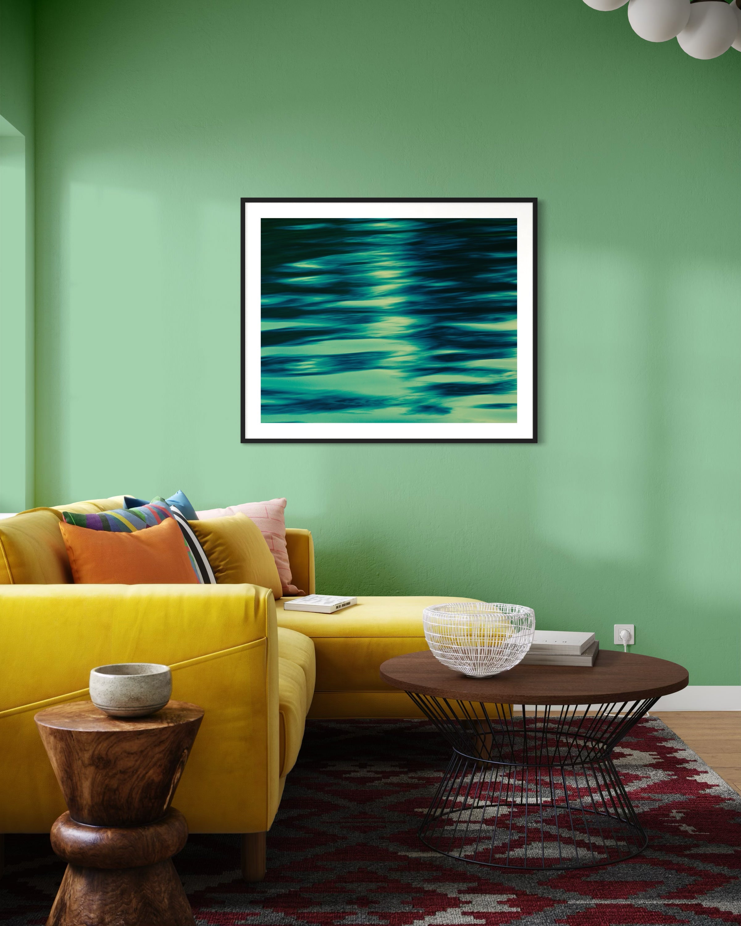 photo of abstract water in lake with blue, green and black in black frame with white matte on light green wall in colorful living room with bright yellow couch