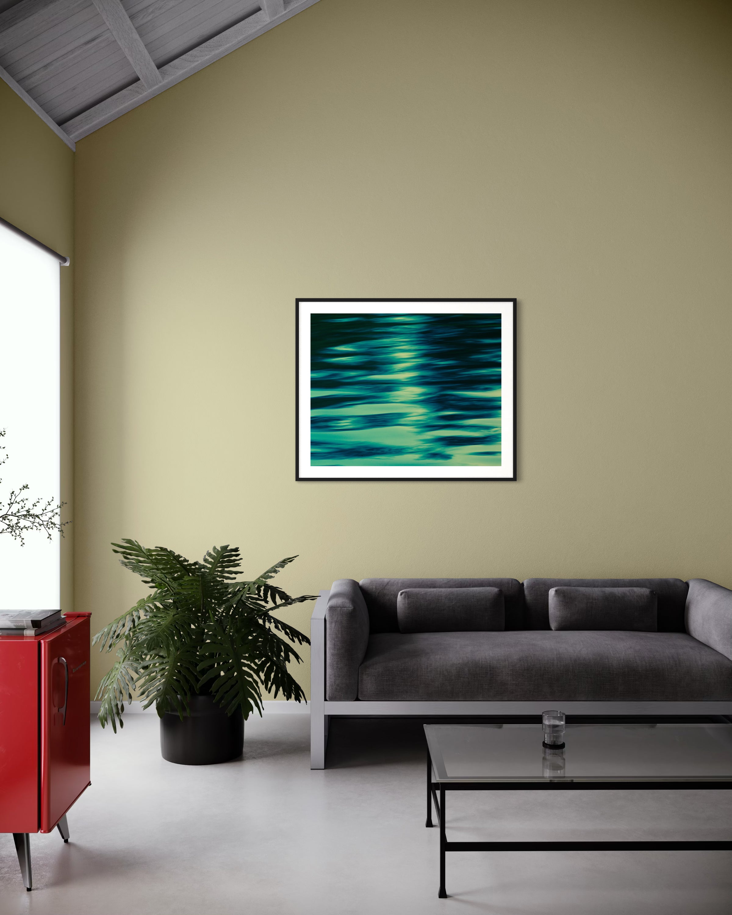 photo of abstract water in lake with blue, green and black in black frame with white matte on light tan wall in minimalist industrial style living room with charcoal gray couch