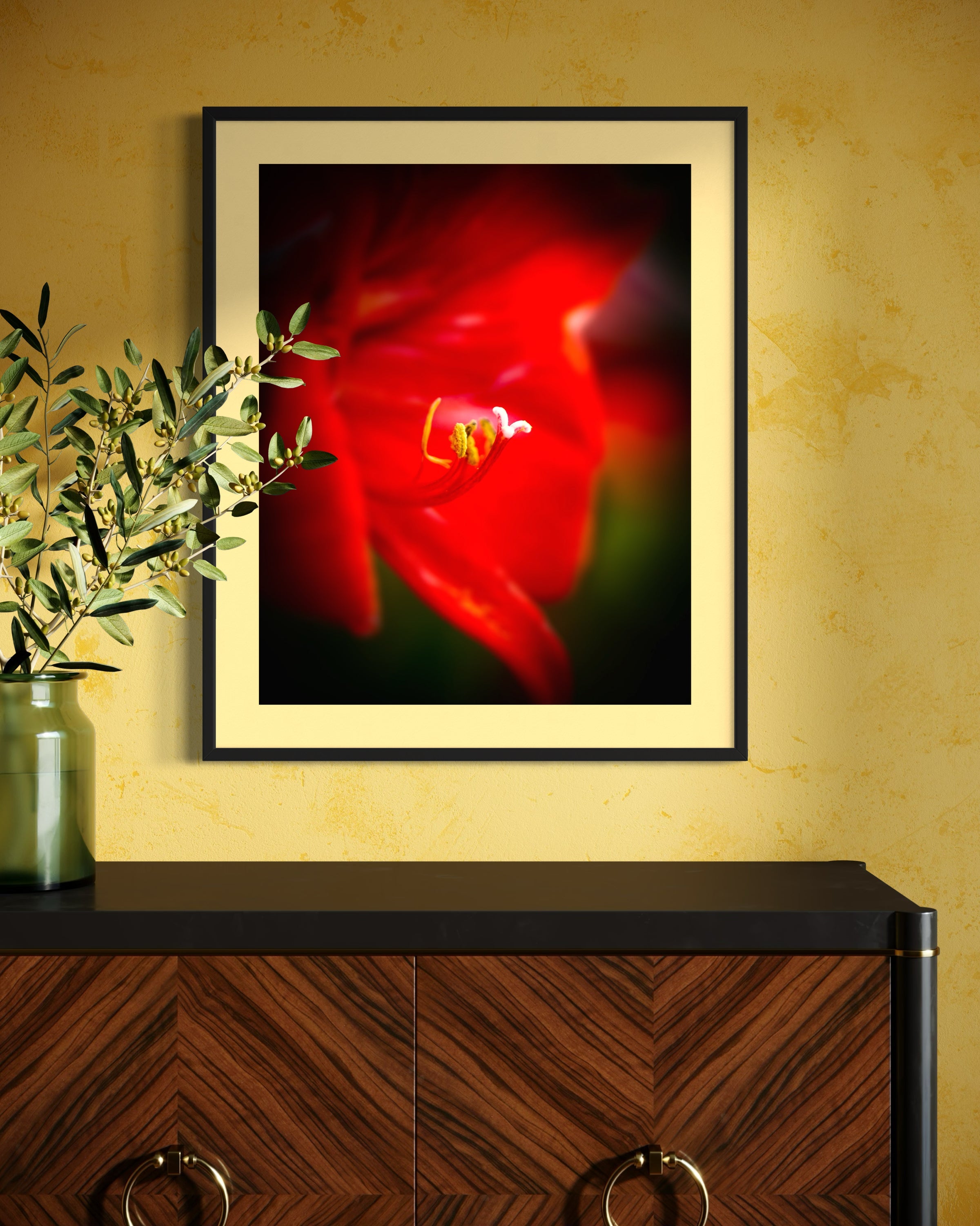macro photo of red flower, selective focus in black frame with pale yellow  matte on yellow wall above wooden table