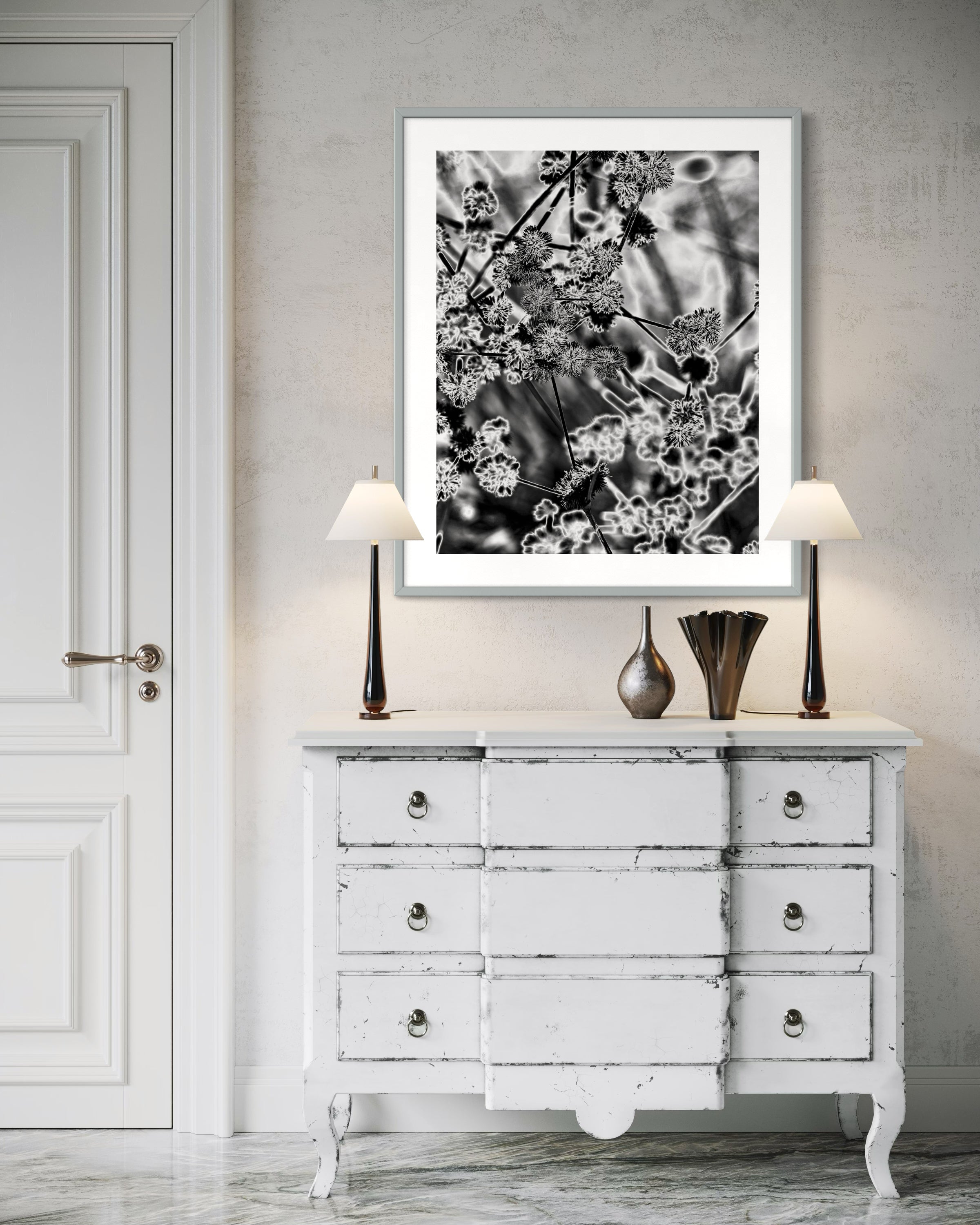 black and white close up of plant with solarized effect in black frame with white matte above rustic off white piece of furniture with drawers 