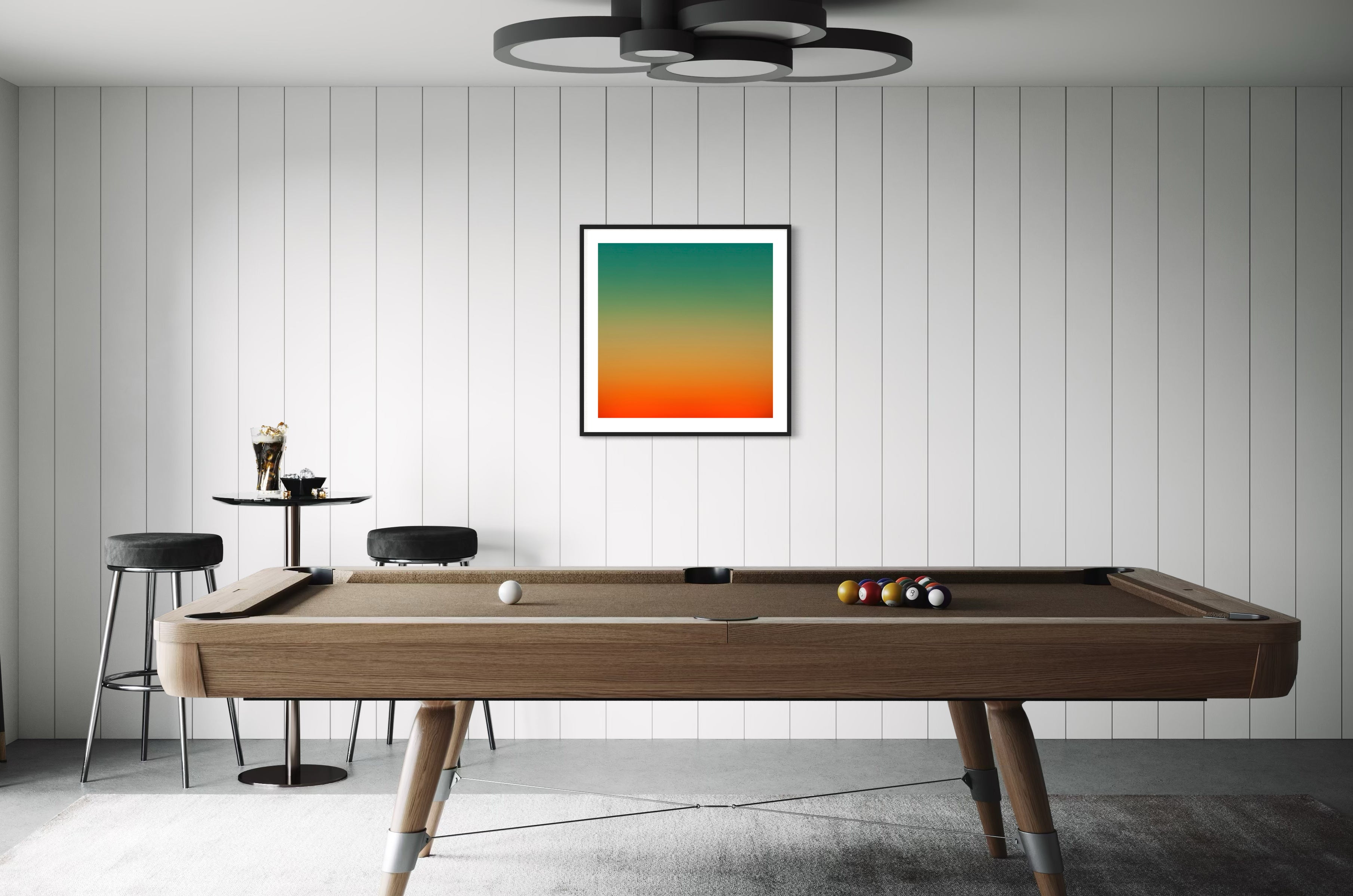 photo, gradient top to bottom teal blue, pale yellow and then orange in black frame with off white matte on off white wall in game room with pool table