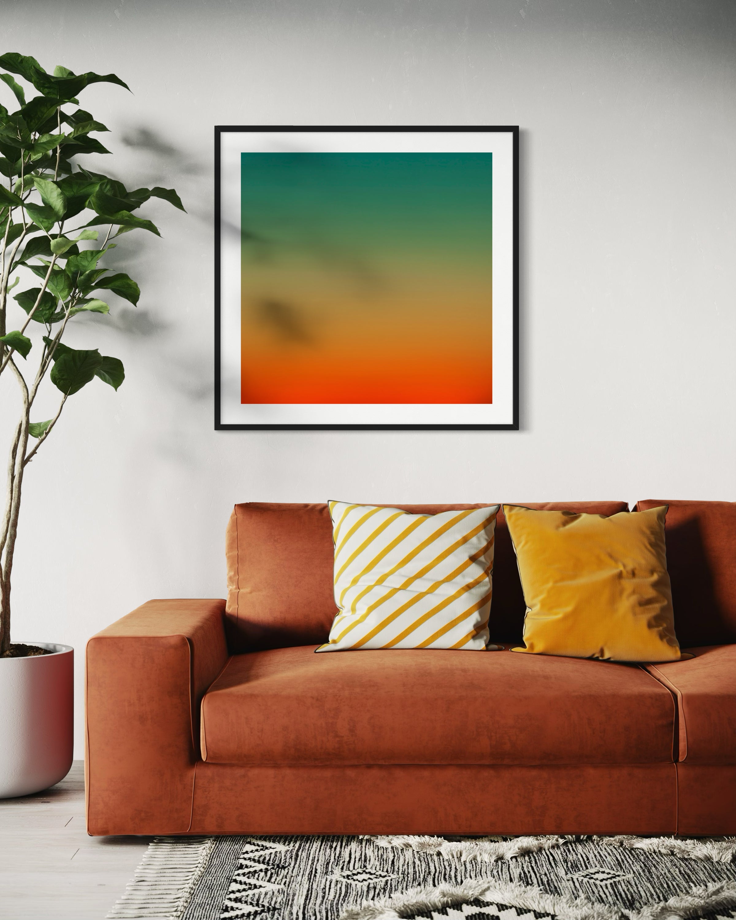 photo, gradient top to bottom teal blue, pale yellow and then orange in teal frame with off white matte on off white wall above orange couch with yellow throw pillows