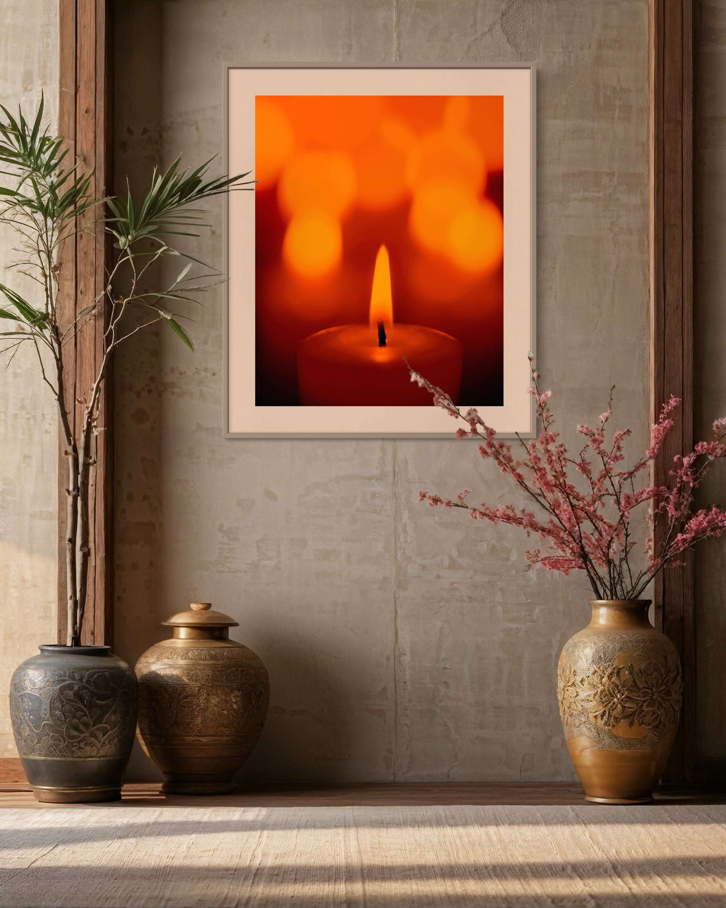 close up photo of single candle with other candles out of focus in the background in black frame with white matte on tan wall in earth toned setting