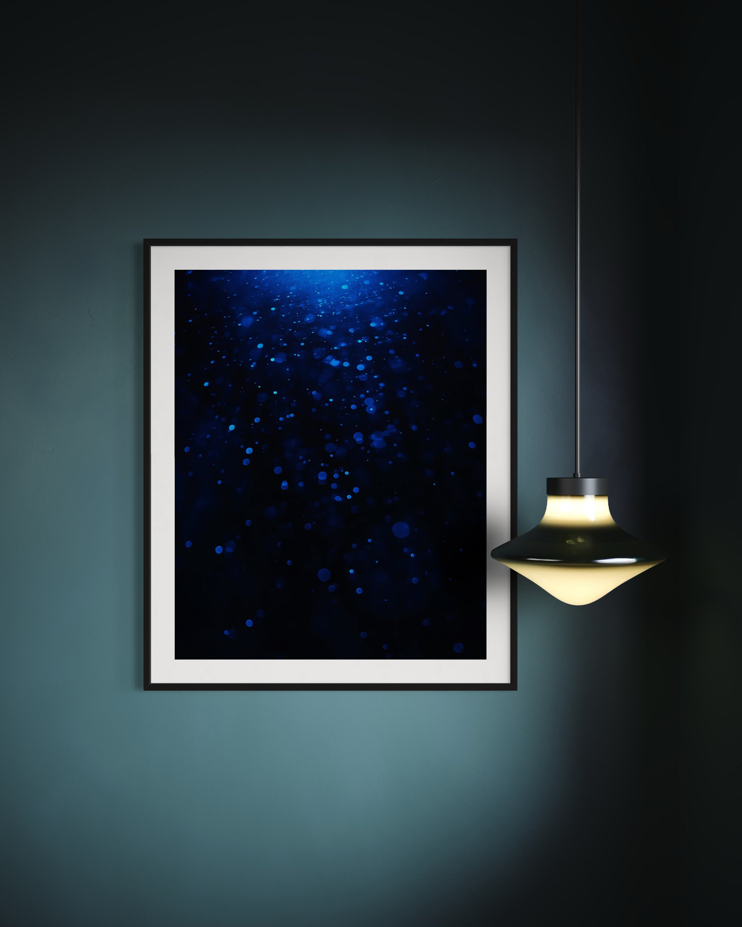 sci fi space looking photo as if close to the exterior of a space ship, blue tone, in black frame with white matte on teal wall with small hanging light fixture 