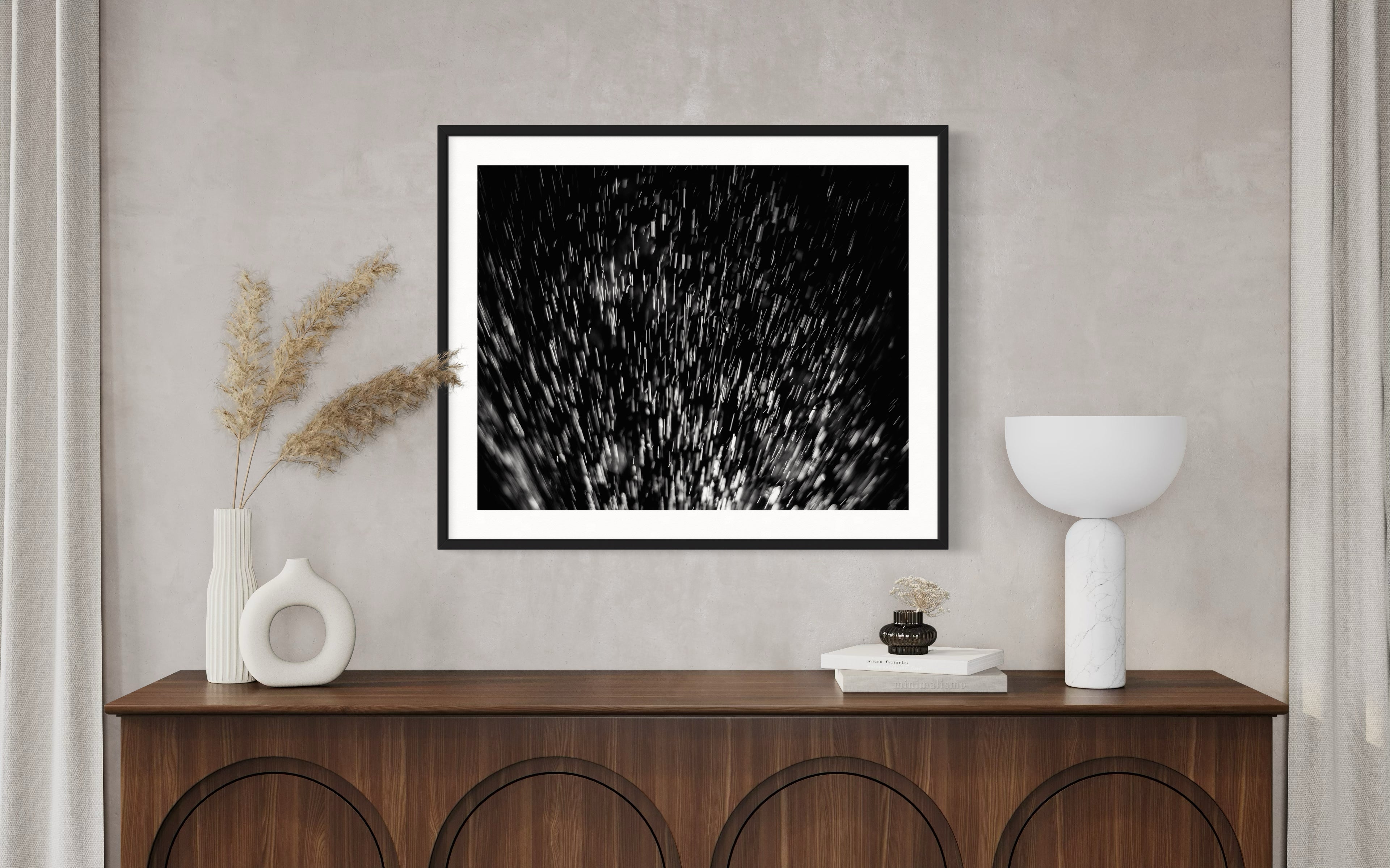 Wooden console with vases, books, and a lamp below a black-and-white abstract art piece on a beige wall. Neutral and minimalist decor.
