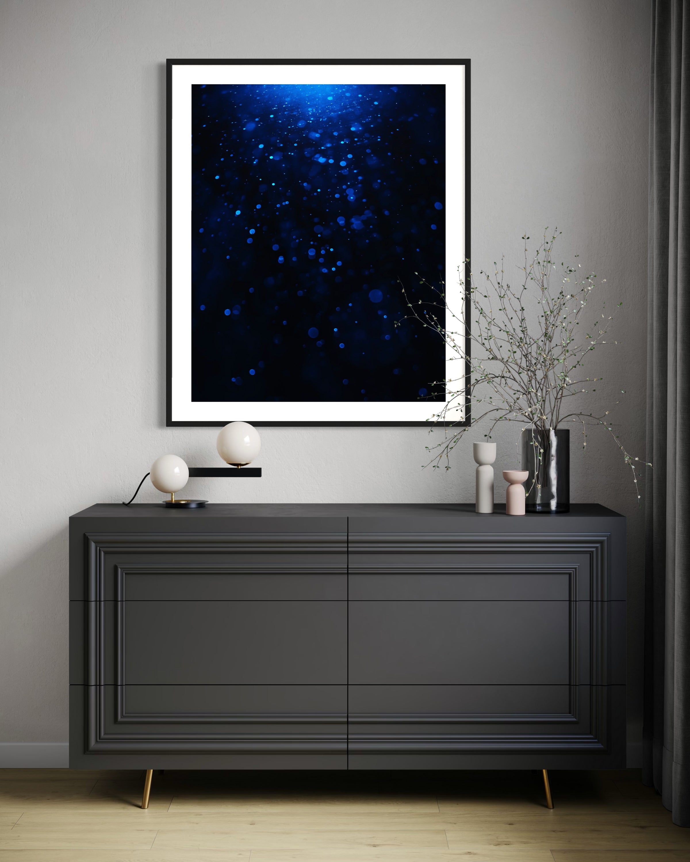 Modern interior with a dark gray dresser against a gray wall, featuring a framed blue abstract art piece.