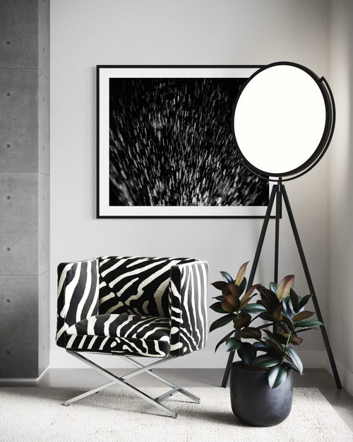 Modern interior with a zebra-patterned chair, round lamp, and framed artwork on a gray wall.