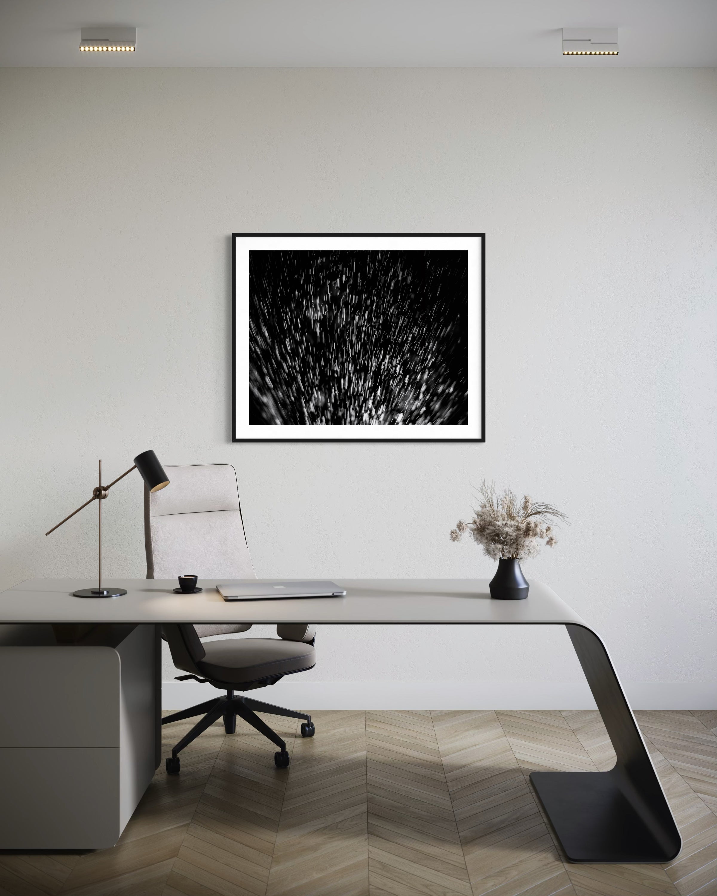 Modern office desk with a chair, lamp, and framed artwork on a white wall.