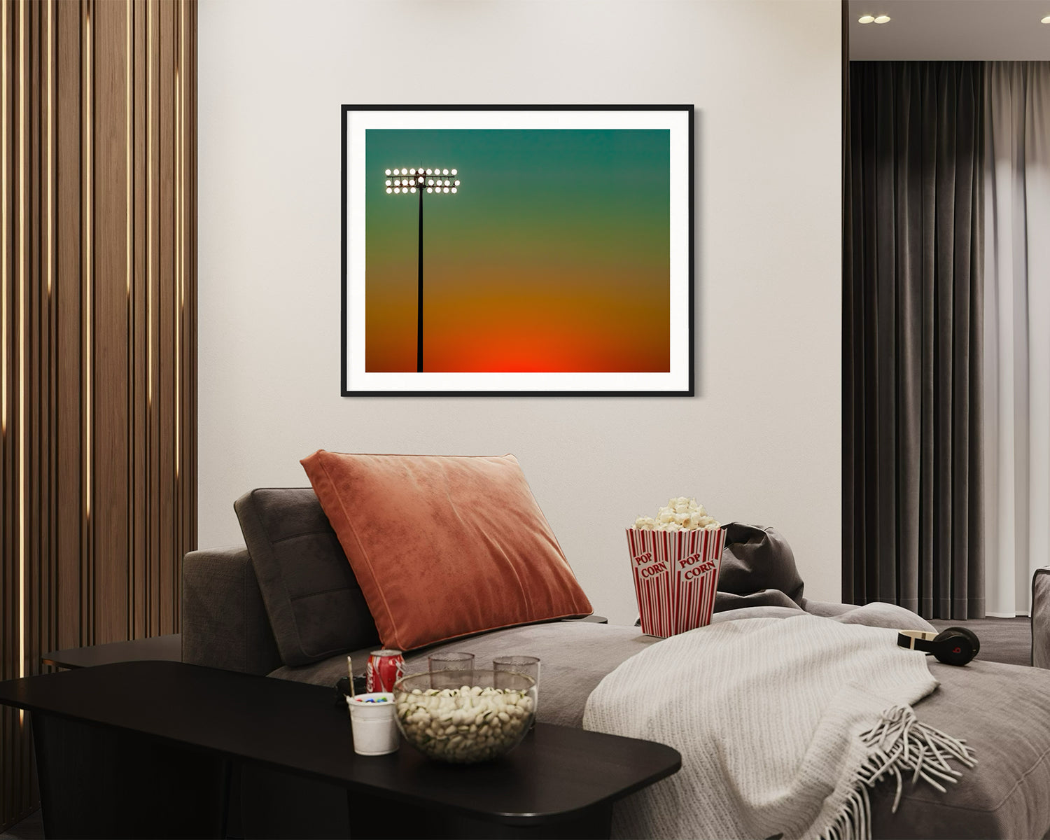 photo of sunset at football stadium single pole of lights left of center, gradient sky teal blue to pale yellow to orange gradient top to bottom in black frame with white matte in game room with popcorn and sodas