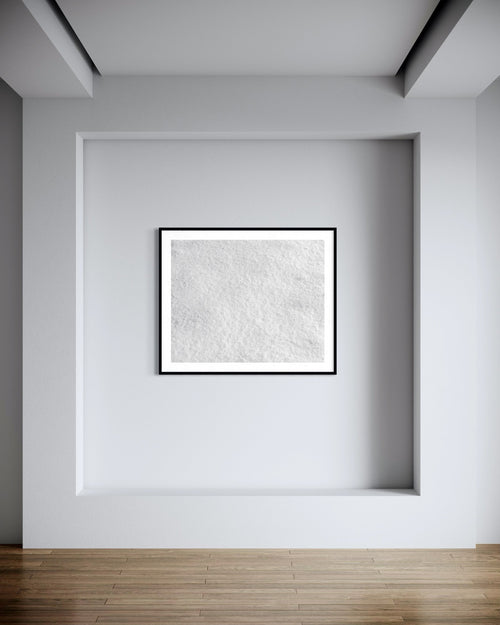 Abstract art piece in a black frame on a white wall