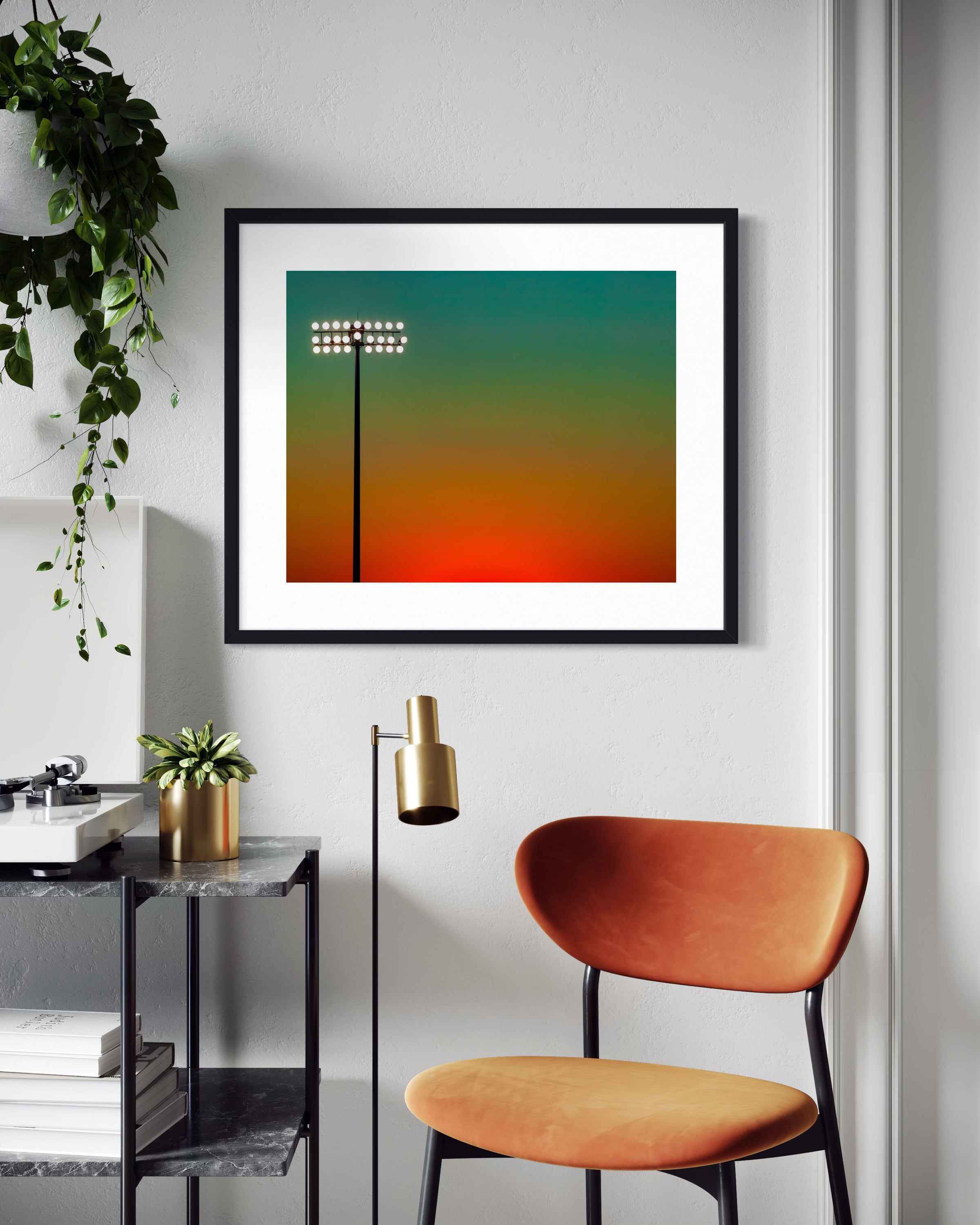photo of stadium light at sunset in black frame on white wall above small chair