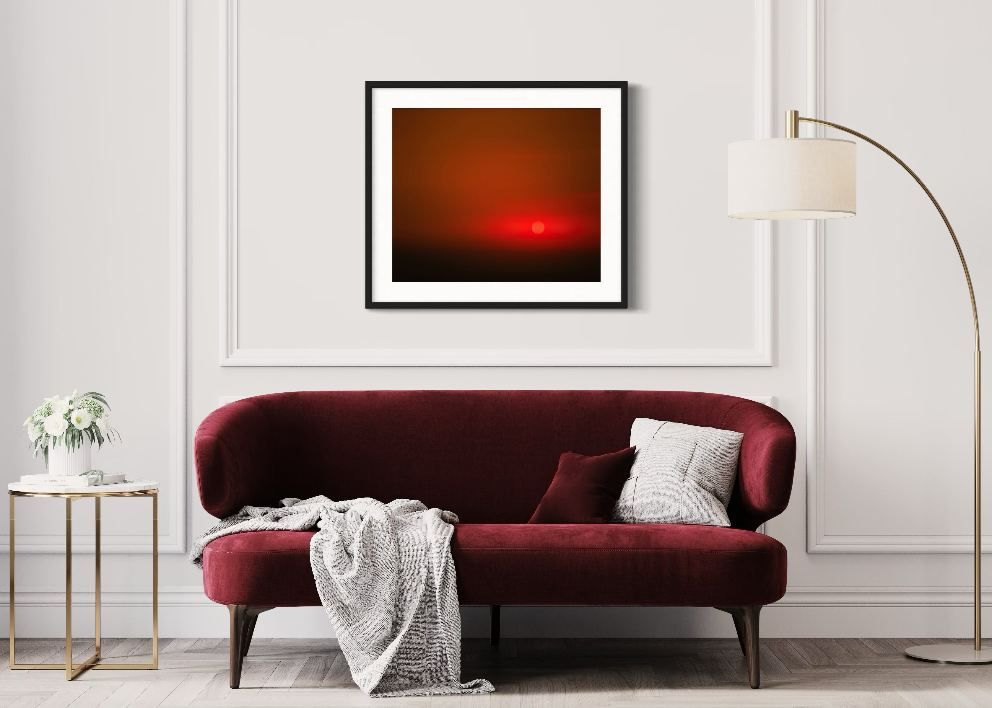 Red sofa in a living room with a framed abstract art piece on the wall.