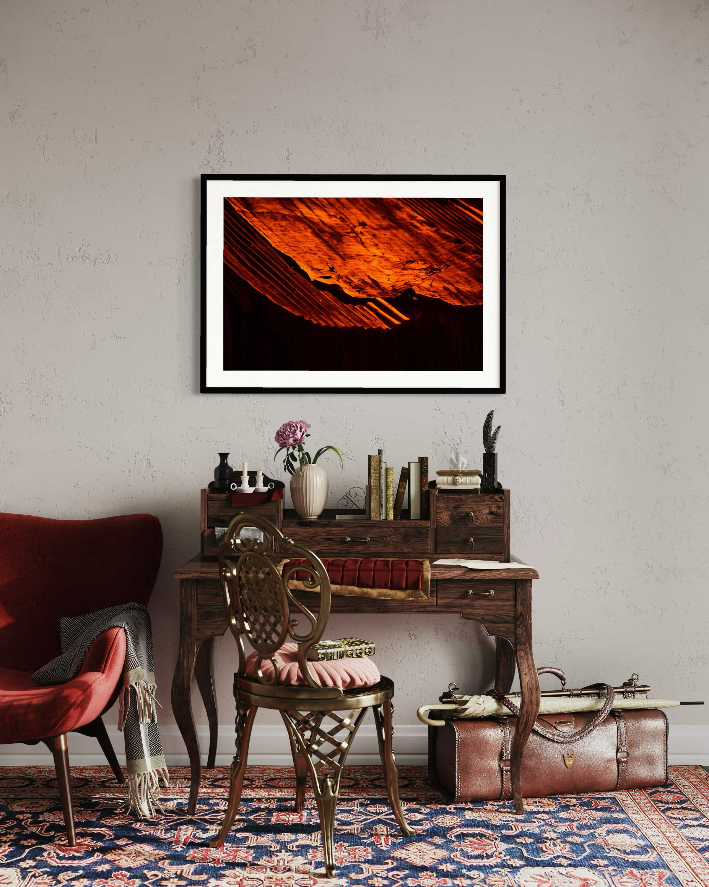 Room interior with a framed artwork, desk, chair, and suitcase.